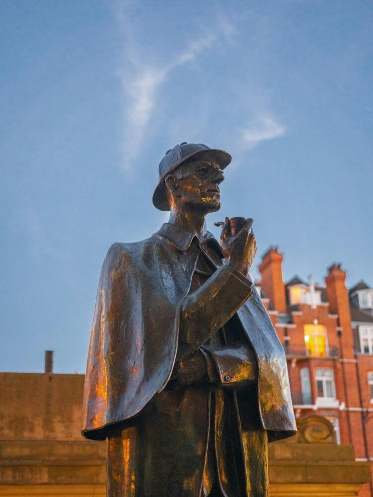 a sherlock holmes statue standing at baker street station in London.